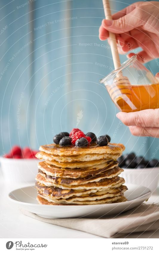 Honig in Pfannkuchen mit Himbeeren und Blaubeeren gießen. Liebling Süßwaren Dessert Frühstück Beeren blau rot backen Lebensmittel Gesunde Ernährung