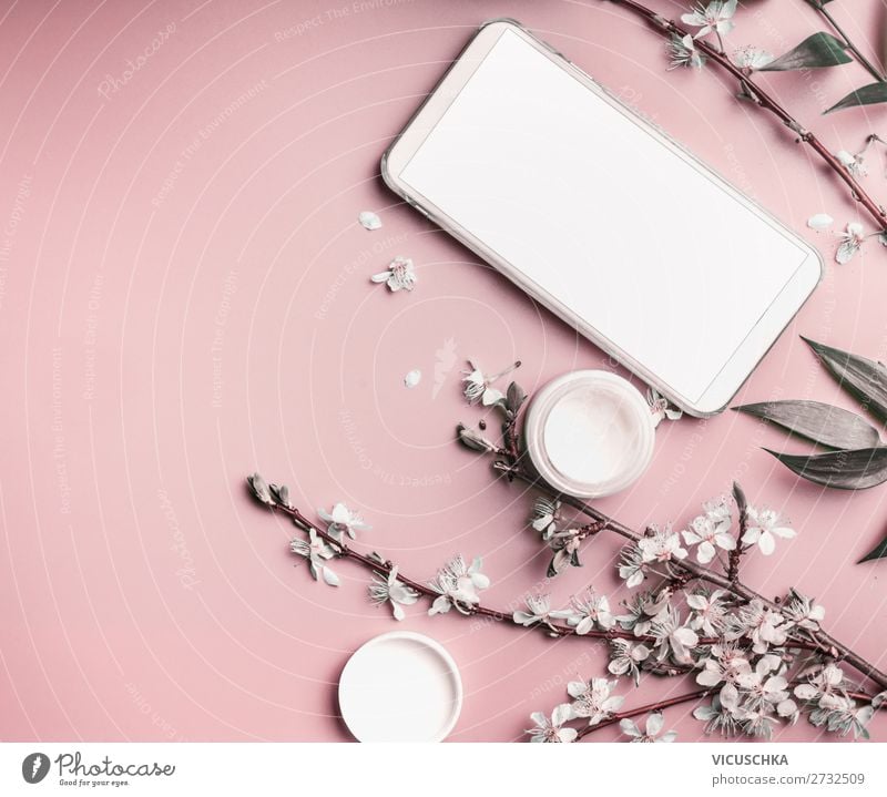 Smartphone-Attrappe auf pastellrosa Desktop mit Kosmetik und Blumen, Ansicht von oben. Schönheitsblog und weibliches Geschäftskonzept Pastell Hintergrund Blüte