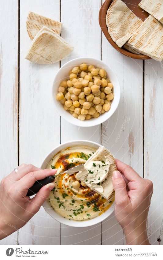 Frau beim Eintauchen von Hummus mit Fladenbrot auf weißem Holztisch Pita Brot Lebensmittel Gesunde Ernährung Foodfotografie Kichererbsen Koriander Zitrone