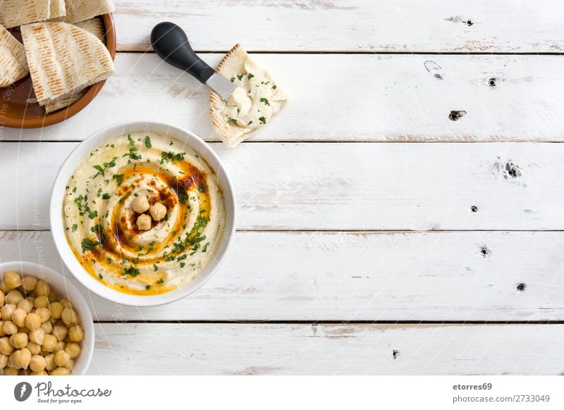 Hummus in der Schüssel und Pita-Brot auf weißem Holztisch. Lebensmittel Gesunde Ernährung Foodfotografie Kichererbsen Koriander Zitrone Olivenöl