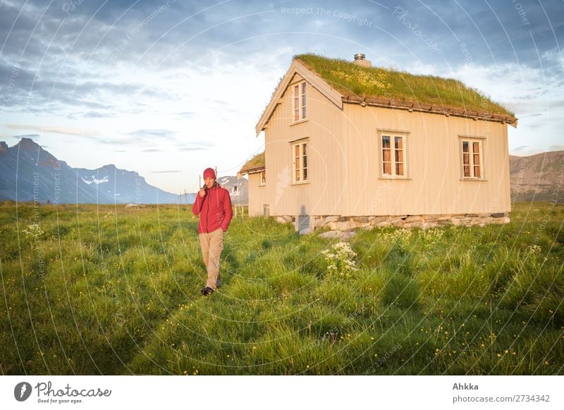 Junger Mann vor norwegischer Hütte in Mitternachtssonne Ferien & Urlaub & Reisen Abenteuer Ferne Sommerurlaub Berge u. Gebirge Jugendliche Gras Norwegen