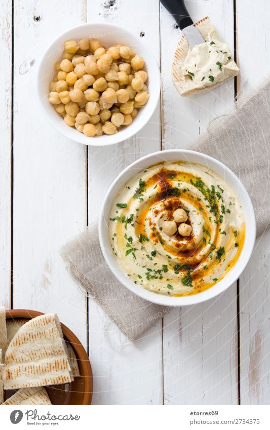 Hummus in der Schale auf weißem Holztisch Pita Brot Lebensmittel Gesunde Ernährung Foodfotografie Kichererbsen Koriander Zitrone Olivenöl Vegane Ernährung