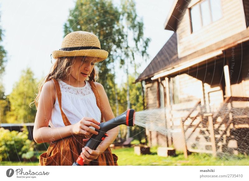 fröhliches Kind Mädchen Blumen gießen mit Schlauch im Sommer Lifestyle Freude Freizeit & Hobby Spielen Garten Arbeit & Erwerbstätigkeit Gartenarbeit Natur