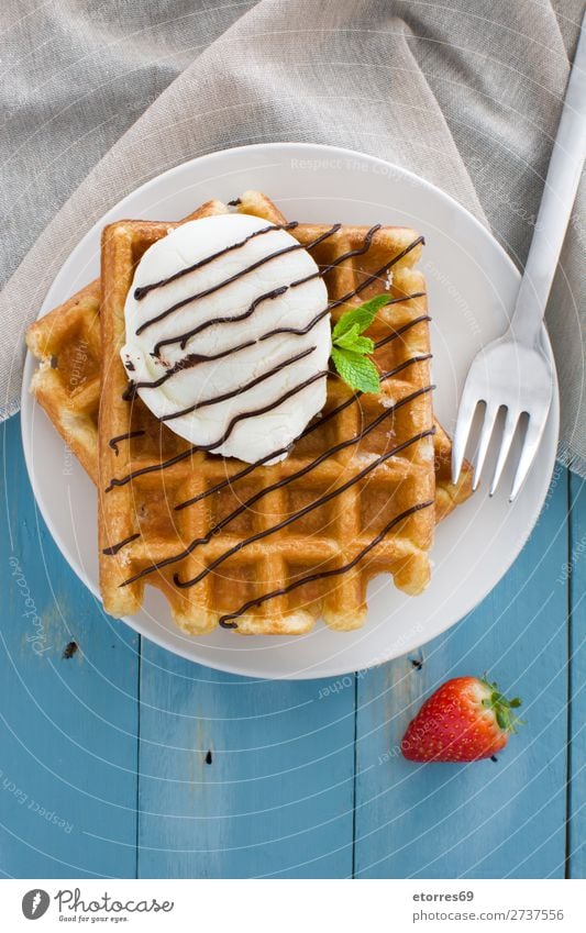 Belgische Waffeln mit Eis auf blauem Holztisch Dessert Speiseeis Belgier Belgien weiß süß Lebensmittel Hintergrund Frühstück Wafer Minze Sirup Haufen Erdbeeren