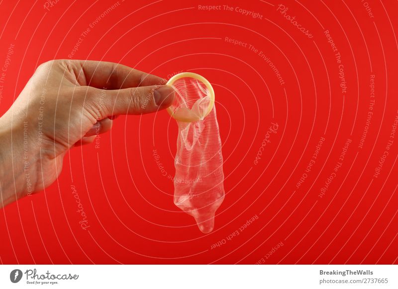 Nahaufnahme Mann Hand hält offenes Kondom über Rot Gesundheit Gesundheitswesen Mensch maskulin Erwachsene Sauberkeit rot Schutz Verantwortung Vorsicht Farbe