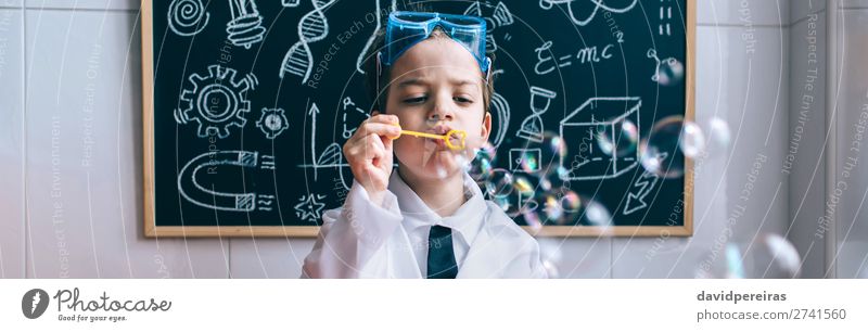 Kind, das Seifenblasen gegen eine gemalte Tafel macht. Flasche Freude Glück Spielen Tisch Wissenschaften Schule Klassenraum Labor Internet Mensch Junge Kindheit