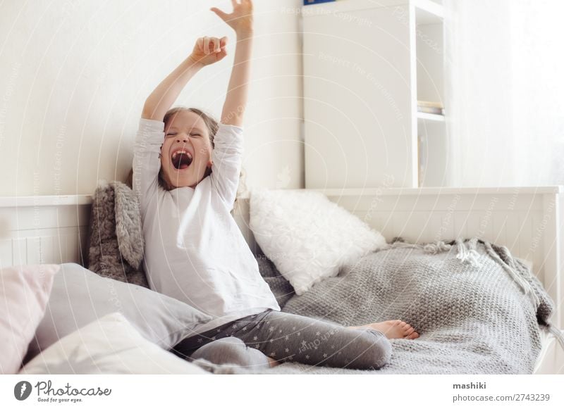 fröhlich schläfriges Kind Mädchen, das sich in ihrem Zimmer ausdehnt. Lifestyle Freude Glück Erholung Spielen Schlafzimmer Kindheit Spielzeug Teddybär Lächeln