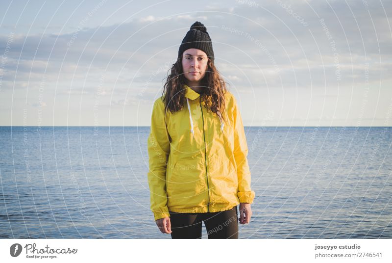 Frau am Strand im Winter Lifestyle Leben Erholung Ausflug Freiheit Sonne Sport Sitzung 30-45 Jahre Erwachsene Natur Horizont Küste Mode Jacke Mantel Hut gelb