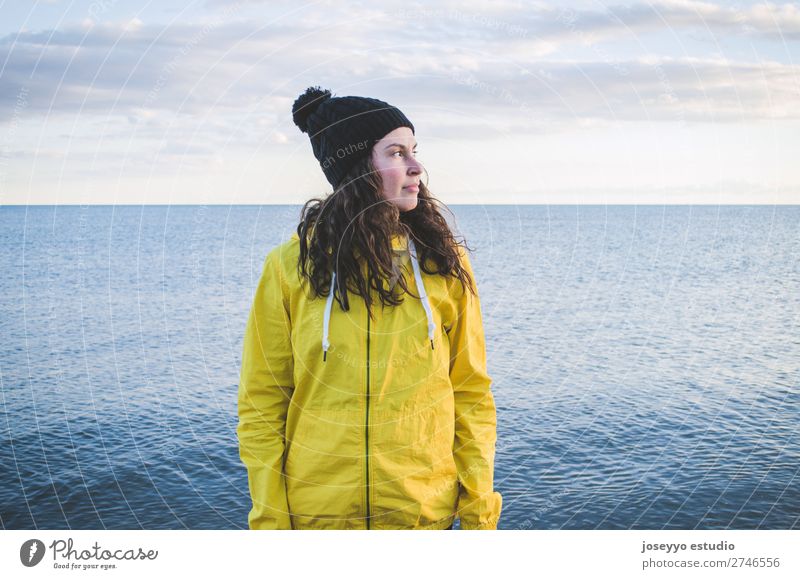 Junge Frau am Strand im Winter Lifestyle Leben Erholung Ausflug Freiheit Sonne Sport Sitzung 30-45 Jahre Erwachsene Natur Horizont Küste Mode Jacke Mantel Hut