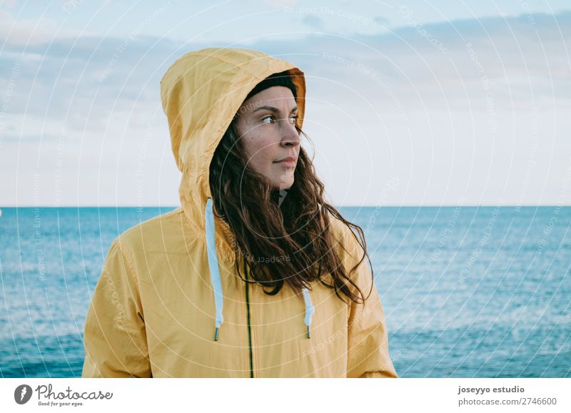 Frau am Strand in einem gelben Regenmantel Lifestyle Leben Erholung Ausflug Freiheit Sonne Winter Sport Sitzung 30-45 Jahre Erwachsene Horizont Küste Mode Jacke