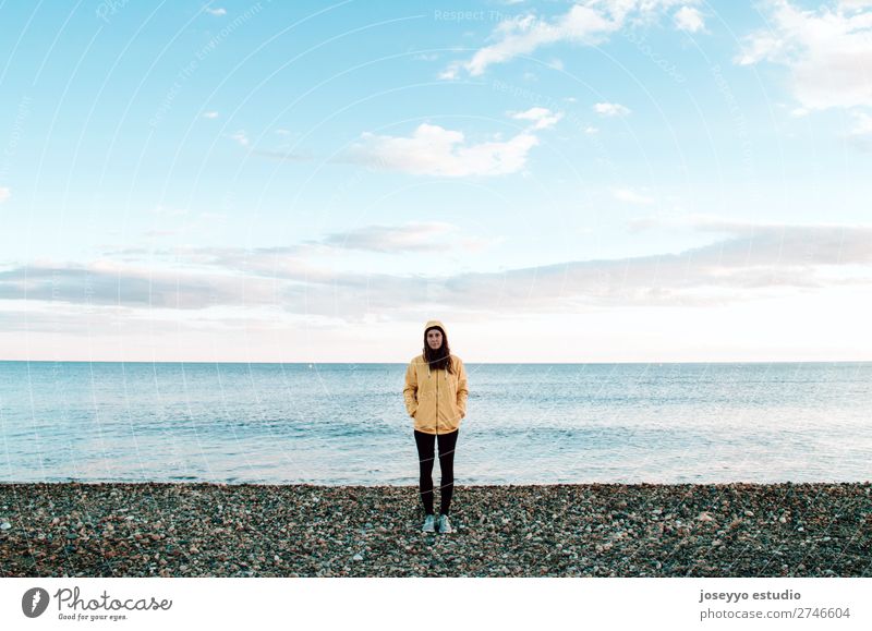 Frau am Strand im Winter Lifestyle Leben Erholung Ausflug Freiheit Sonne Sport Sitzung 30-45 Jahre Erwachsene Natur Horizont Küste Mode Jacke Mantel Hut gelb