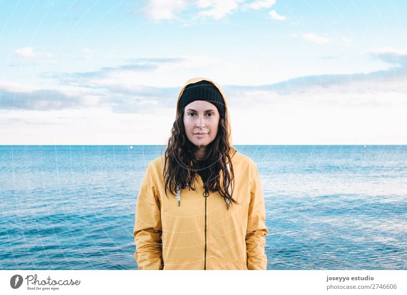 Junge Frau am Strand Lifestyle Leben Erholung Ausflug Freiheit Sonne Winter Sport Sitzung 30-45 Jahre Erwachsene Natur Horizont Küste Mode Jacke Mantel Hut