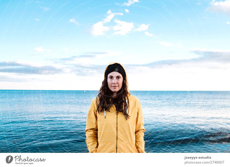 Frau am Strand im Winter Lifestyle Leben Ausflug Freiheit Sonne Sport Sitzung 30-45 Jahre Erwachsene Natur Horizont Küste Mode Jacke Mantel Hut Lächeln gelb