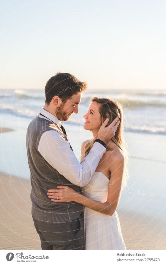 Zärtlich küssendes Brautpaar im Sonnenlicht Paar Hochzeit Strand umarmend Engagement Zufriedenheit Valentinsgruß Genuss verliebt Meereslandschaft stehen