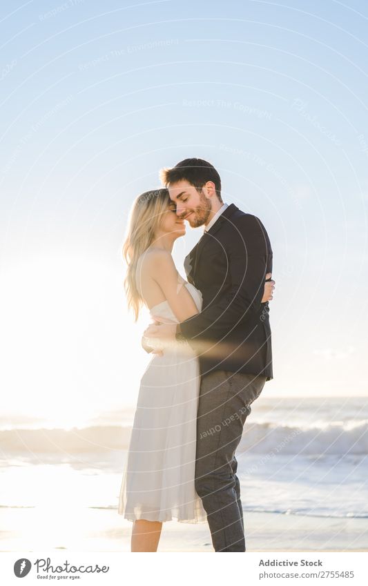 Zärtlich küssendes Brautpaar im Sonnenlicht Paar Hochzeit Strand umarmend Engagement Zufriedenheit Valentinsgruß Genuss verliebt Meereslandschaft stehen