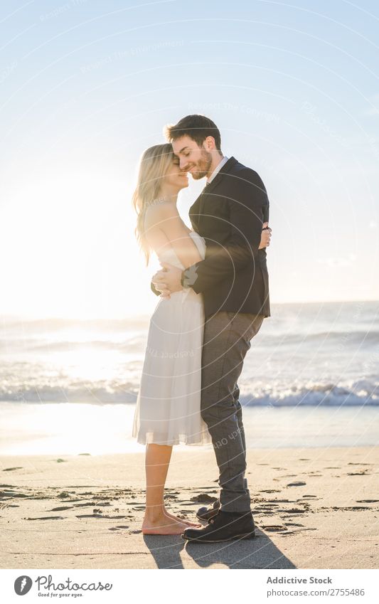 Zärtlich küssendes Brautpaar im Sonnenlicht Paar Hochzeit Strand umarmend Engagement Zufriedenheit Valentinsgruß Genuss verliebt Meereslandschaft stehen