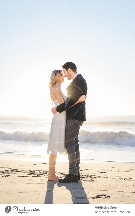 Zärtlich küssendes Brautpaar im Sonnenlicht Paar Hochzeit Strand umarmend Engagement Zufriedenheit Valentinsgruß Genuss verliebt Meereslandschaft stehen