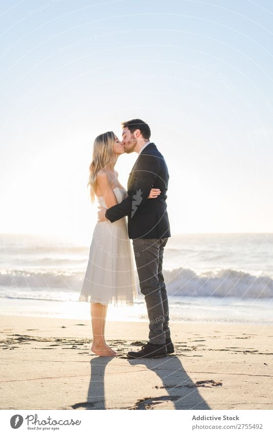 Zärtlich küssendes Brautpaar im Sonnenlicht Paar Hochzeit Strand umarmend Engagement Zufriedenheit Valentinsgruß Genuss verliebt Meereslandschaft stehen