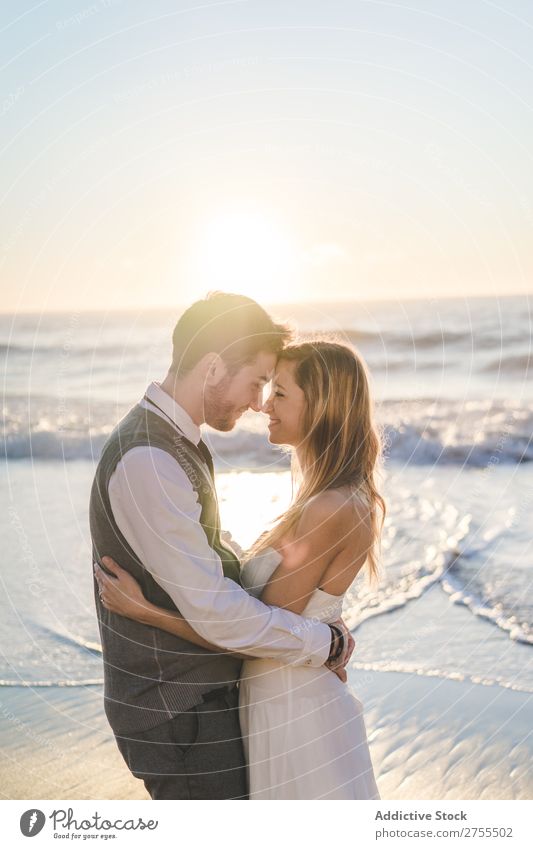 Zärtlich küssendes Brautpaar im Sonnenlicht Paar Hochzeit Strand umarmend Engagement Zufriedenheit Valentinsgruß Genuss verliebt Meereslandschaft stehen