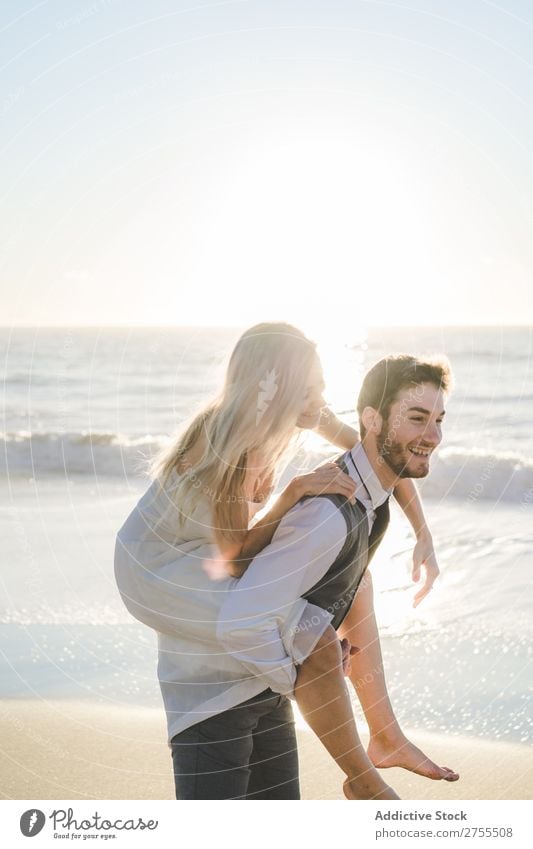 Bräutigam mit charmantem Mädchen auf dem Rücken Paar Hochzeit auf der Rückseite Strand Sommer Meer striegeln verliebt Braut tragen Erholung lachen heiter Kleid