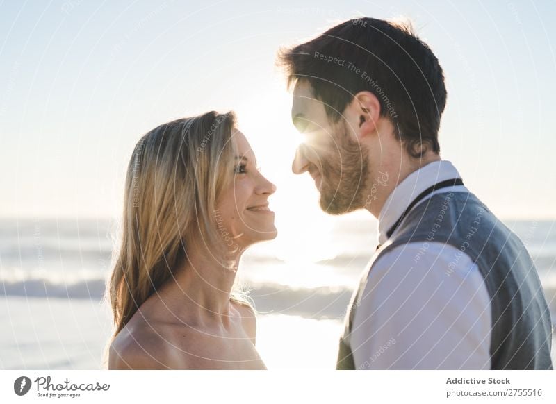 Zärtlich küssendes Brautpaar im Sonnenlicht Paar Hochzeit Strand umarmend Engagement Zufriedenheit Valentinsgruß Genuss verliebt Meereslandschaft stehen