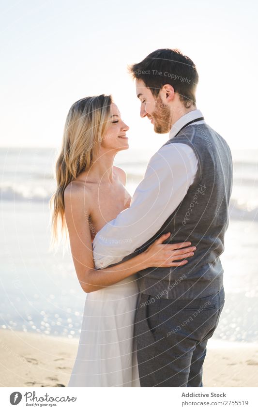 Zärtlich küssendes Brautpaar im Sonnenlicht Paar Hochzeit Strand umarmend Engagement Zufriedenheit Valentinsgruß Genuss verliebt Meereslandschaft stehen