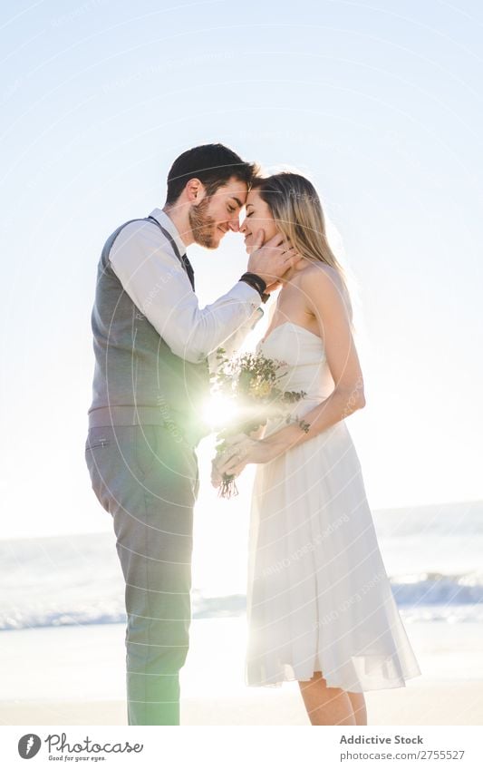 Braut mit Blumenstrauß, der den Bräutigam umarmt. Paar hochzeitlich Umarmen Feste & Feiern Hochzeit Natur romantisch Strand reisend Liebe rustikal Zusammensein