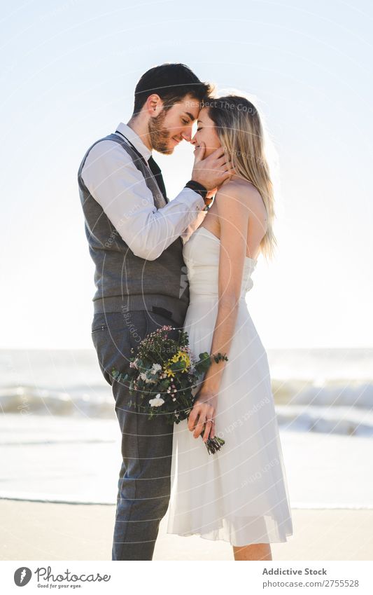 Braut mit Blumenstrauß, der den Bräutigam umarmt. Paar hochzeitlich Umarmen Feste & Feiern Hochzeit Natur romantisch Strand reisend Liebe rustikal Zusammensein