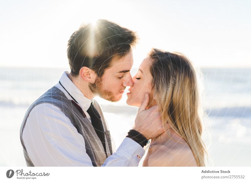 Zärtlich küssendes Brautpaar im Sonnenlicht Paar Hochzeit Strand umarmend Engagement Zufriedenheit Valentinsgruß Genuss verliebt Meereslandschaft stehen