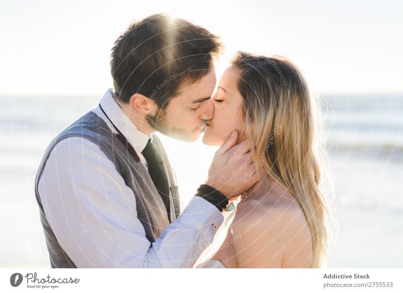 Zärtlich küssendes Brautpaar im Sonnenlicht Paar Hochzeit Strand umarmend Engagement Zufriedenheit Valentinsgruß Genuss verliebt Meereslandschaft stehen