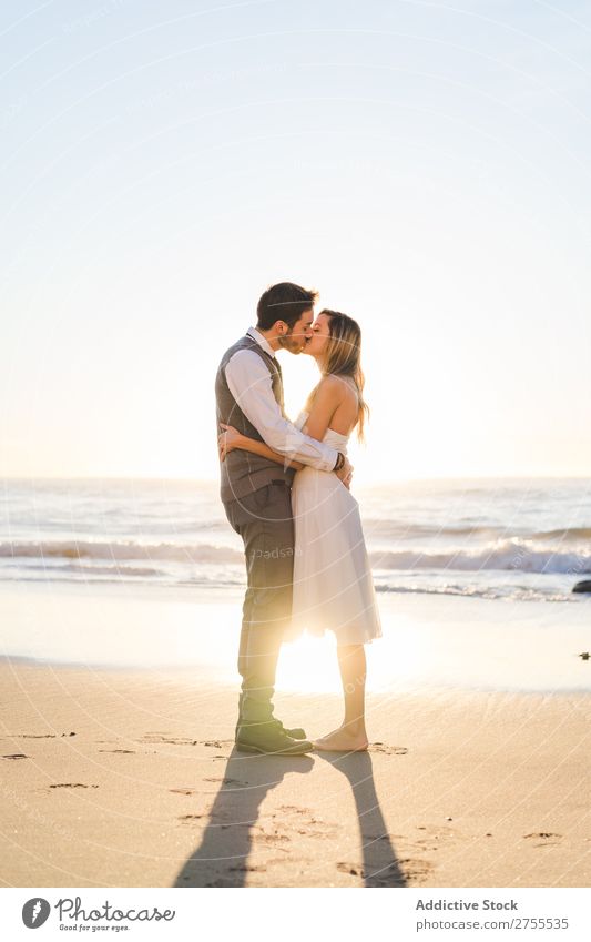 Zärtlich küssendes Brautpaar im Sonnenlicht Paar Hochzeit Strand umarmend Engagement Zufriedenheit Valentinsgruß Genuss verliebt Meereslandschaft stehen