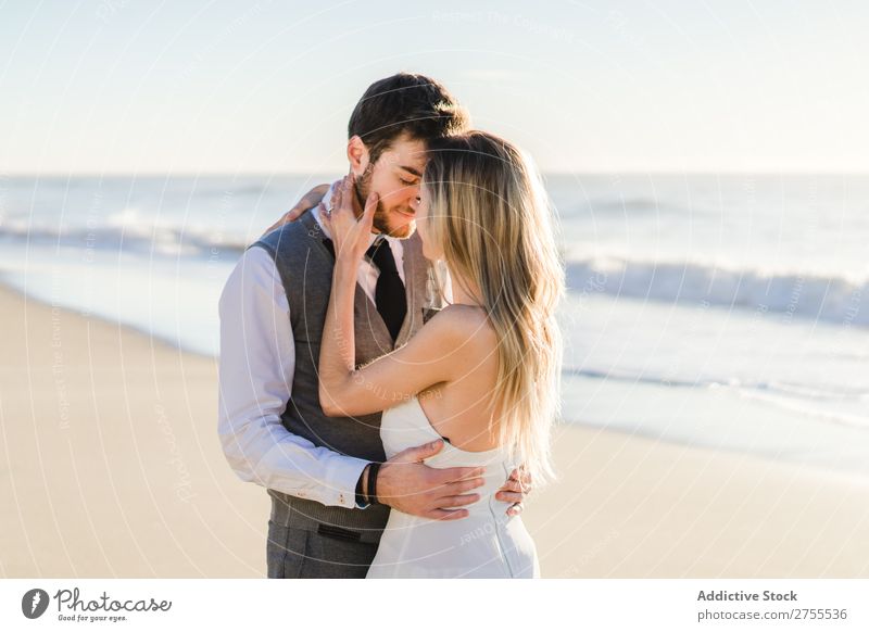 Zärtlich küssendes Brautpaar im Sonnenlicht Paar Hochzeit Strand umarmend Engagement Zufriedenheit Valentinsgruß Genuss verliebt Meereslandschaft stehen