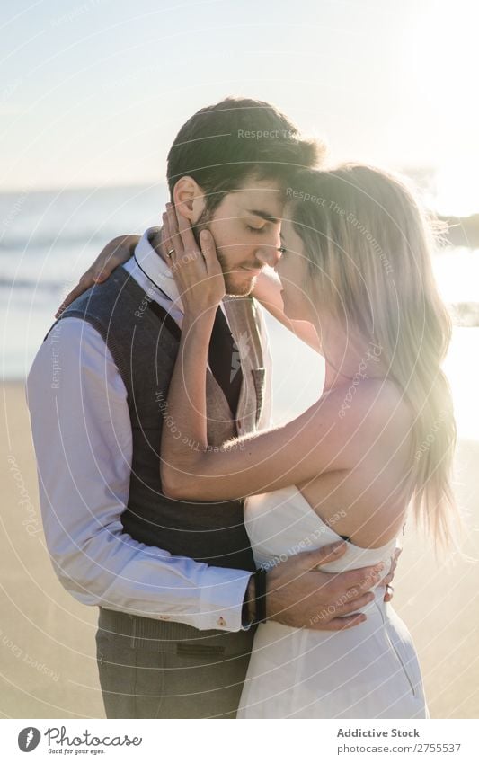 Zärtlich küssendes Brautpaar im Sonnenlicht Paar Hochzeit Strand umarmend Engagement Zufriedenheit Valentinsgruß Genuss verliebt Meereslandschaft stehen