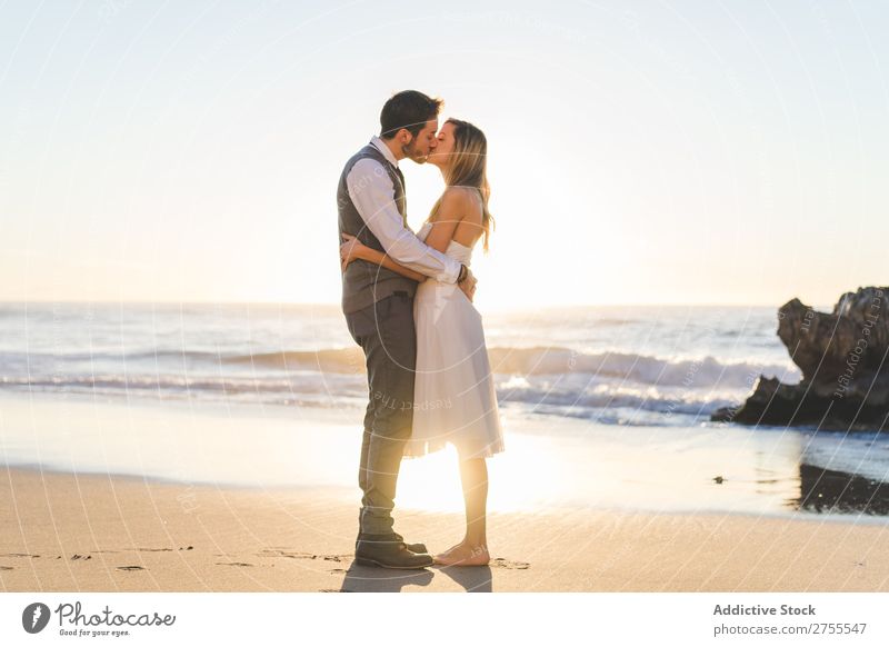 Zärtlich küssendes Brautpaar im Sonnenlicht Paar Hochzeit Strand umarmend Engagement Zufriedenheit Valentinsgruß Genuss verliebt Meereslandschaft stehen