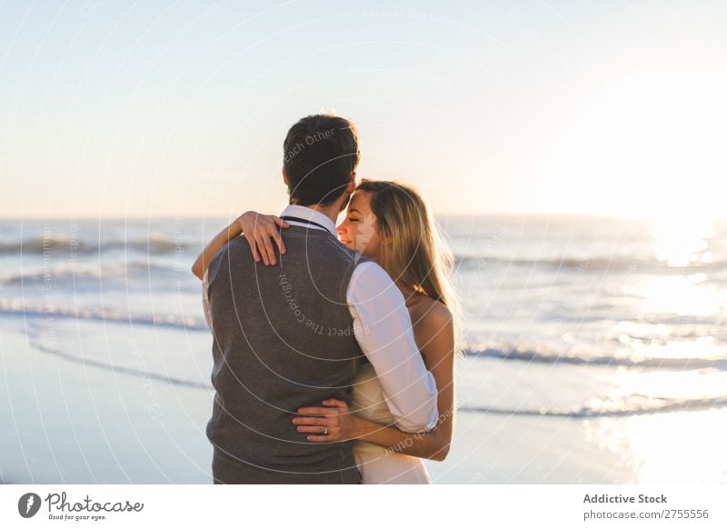 Zärtlich küssendes Brautpaar im Sonnenlicht Paar Hochzeit Strand umarmend Engagement Zufriedenheit Valentinsgruß Genuss verliebt Meereslandschaft stehen