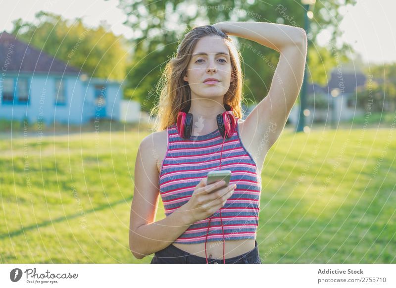 Stylisches Mädchen, das mit Gadgets posiert. Frau PDA Körperhaltung Erholung Sommer Natur Kopfhörer feminin Musik Zufriedenheit träumen Wiese Halt Gerät