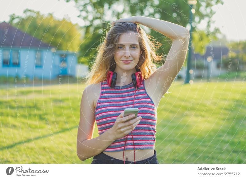 Stylisches Mädchen, das mit Gadgets posiert. Frau PDA Körperhaltung Erholung Sommer Natur Kopfhörer feminin Musik Zufriedenheit träumen Wiese Halt Gerät