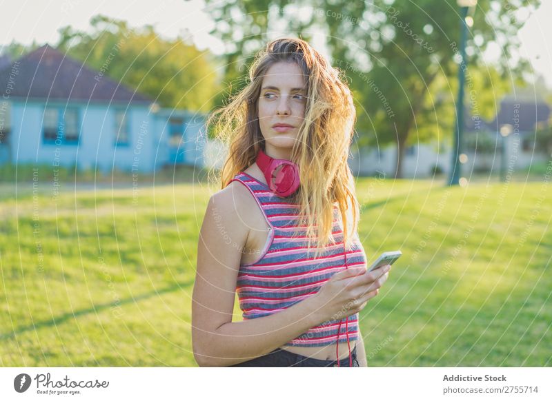 Stylisches Mädchen, das mit Gadgets posiert. Frau PDA Körperhaltung Erholung Sommer Natur Kopfhörer feminin Musik Zufriedenheit träumen Wiese Halt Gerät