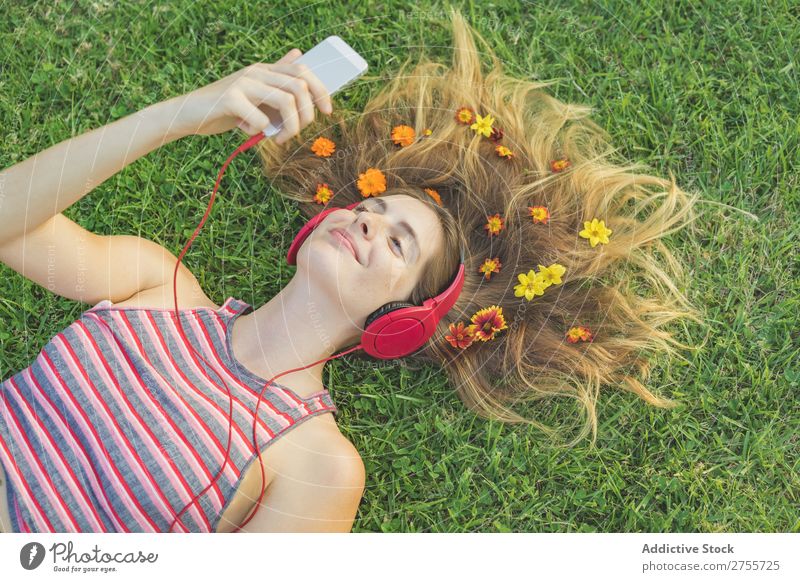 Mädchen mit Gadgets auf dem Rasen Frau Kopfhörer Erholung PDA feminin Musik träumen Blume Wiese Entertainment Schüler Park Sommer Freiheit Zufriedenheit Natur