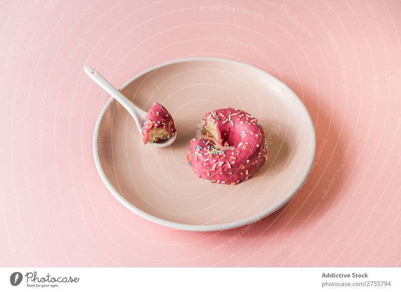 Süßer rosa Doughnut auf Teller Krapfen beißen Studioaufnahme lecker Dessert Kunst süß Spielfigur Süßwaren Feinschmecker Ernährung Kreativität Essen Löffel