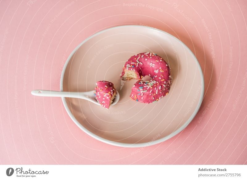 Süßer rosa Doughnut auf Teller Krapfen beißen Studioaufnahme lecker Dessert Kunst süß Spielfigur Süßwaren Feinschmecker Ernährung Kreativität Essen Löffel