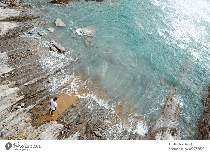 Mann, der auf einem felsigen Strand steht. Tourist Klippe Meer Felsen Ferien & Urlaub & Reisen Tourismus Natur Landschaft Küste Wasser Sonne Freiheit Stein