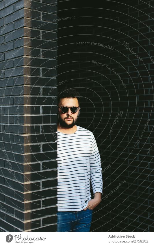 Selbstbewusster Mann mit stylischer Sonnenbrille Blick in die Kamera Fürsorge besinnlich Stil Backstein Wand stehen selbstbewußt Jugendliche Coolness Mensch