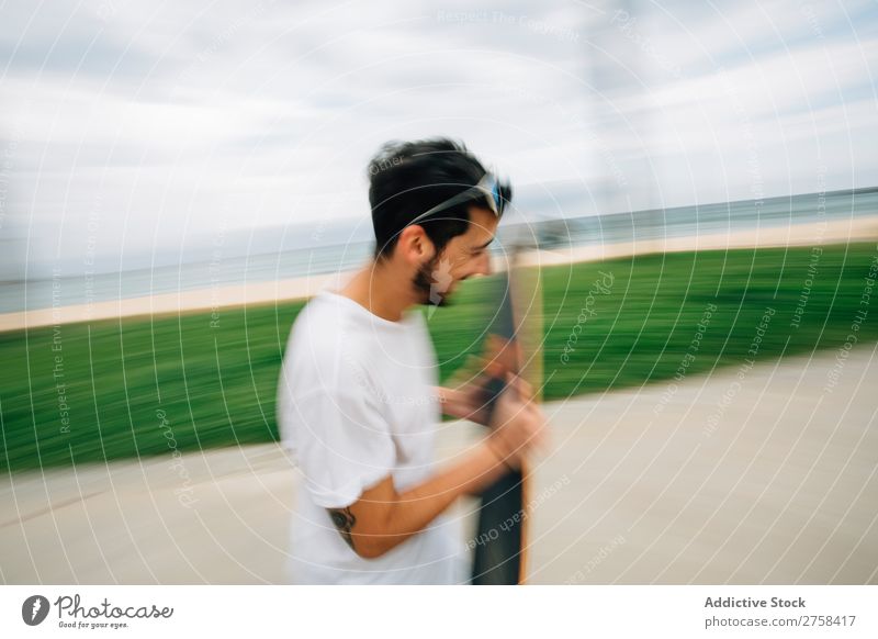 Mann im Sommeroutfit beim Schlittschuhlaufen auf der Straße am Meer. Freude rennen Unschärfe Außenaufnahme Aktion Ausritt sportlich Schlittschuhe Skater