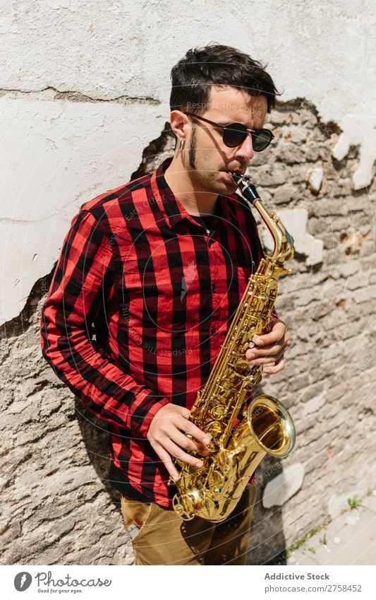 Lächelnder Jazzmann mit Saxophon Musiker Mann Sonnenbrille selbstbewußt Coolness heiter Wand Jugendliche Instrument Musical Leistung Saxophonspieler Mensch