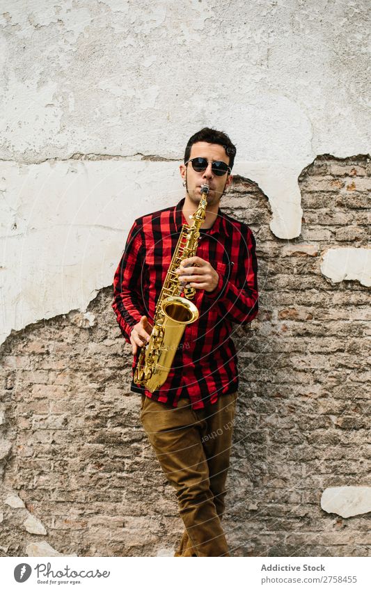 Lächelnder Jazzmann mit Saxophon Musiker Mann Sonnenbrille selbstbewußt Coolness heiter Wand Jugendliche Instrument Musical Leistung Saxophonspieler Mensch