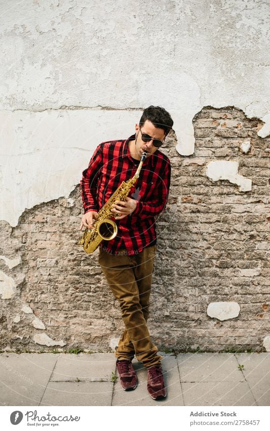 Lächelnder Jazzmann mit Saxophon Musiker Mann Sonnenbrille selbstbewußt Coolness heiter Wand Jugendliche Instrument Musical Leistung Saxophonspieler Mensch