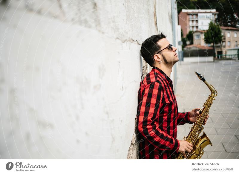 Lächelnder Jazzmann mit Saxophon Musiker Mann Sonnenbrille selbstbewußt Coolness heiter Wand Jugendliche Instrument Musical Leistung Saxophonspieler Mensch