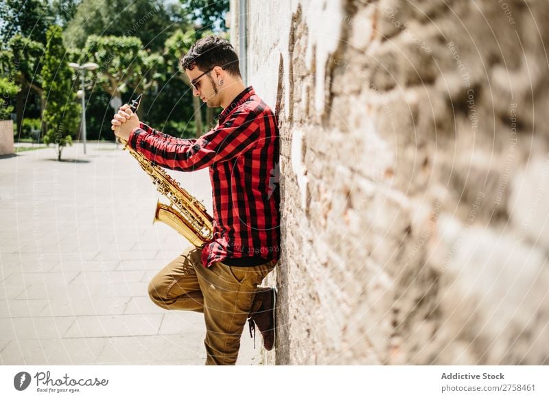 Lächelnder Jazzmann mit Saxophon Musiker Mann Sonnenbrille selbstbewußt Coolness heiter Wand Jugendliche Instrument Musical Leistung Saxophonspieler Mensch