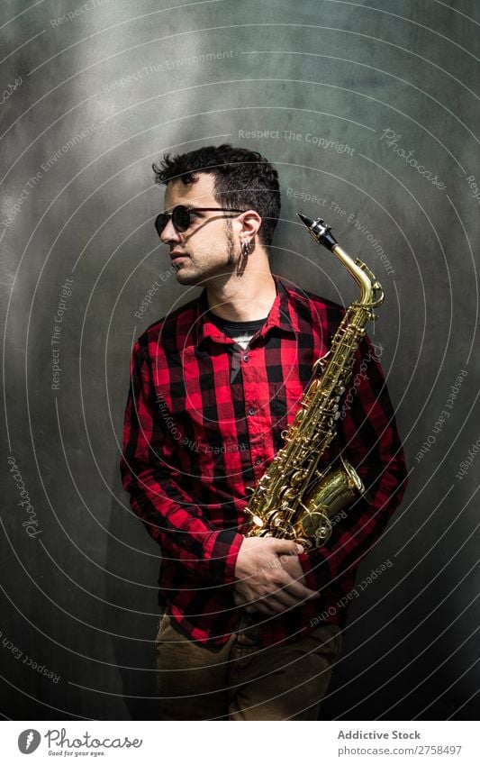 Seitenansicht des jungen Saxophonisten im Stehen mit lehnendem Instrument Musiker Mann Jugendliche Jazz Musical Leistung Saxophonspieler Mensch Spieler Artist